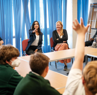 Claire is pointing at a pupil who is raising his hand.